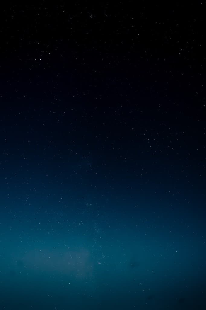 Man on his phone in a lit apartment doorway at night