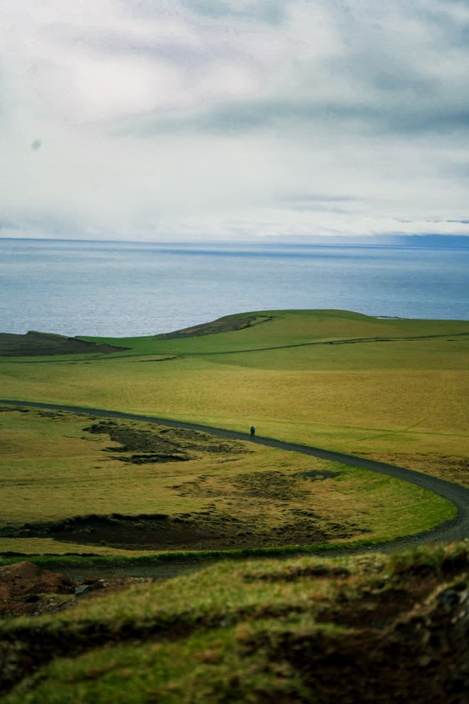 Lone figure on a winding road above the sea, Iceland