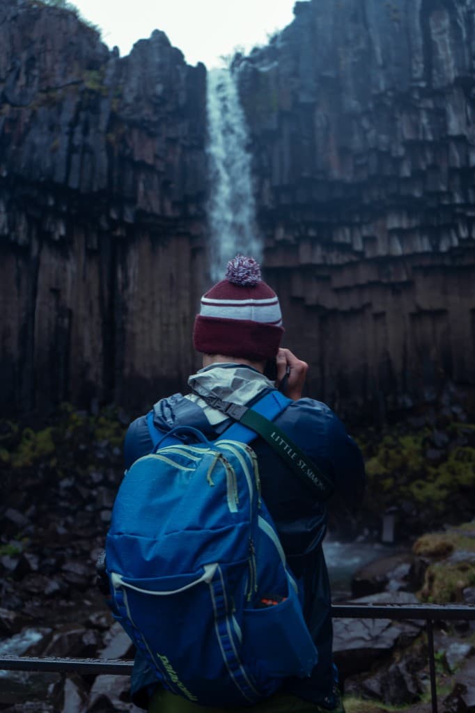 Hiker leaning on a railing above a mossy canyon